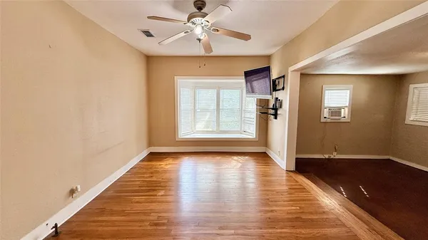 a view of an empty room with window and wooden floor