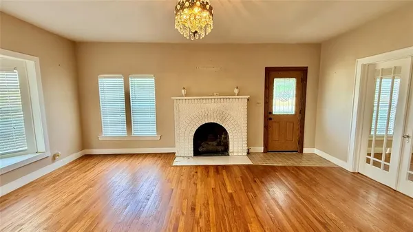 an empty room with windows a fireplace and wooden floor