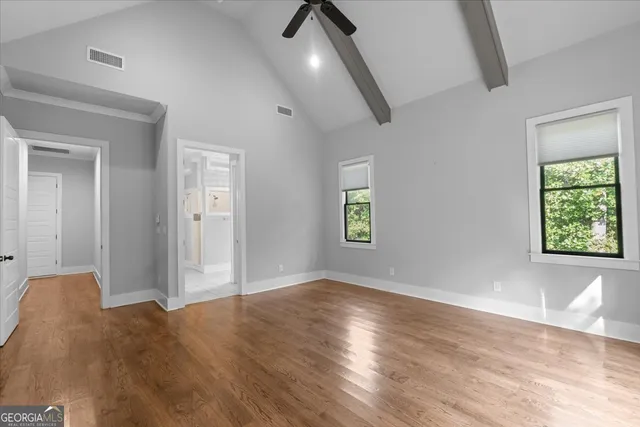 an empty room with wooden floor chandelier fan and windows
