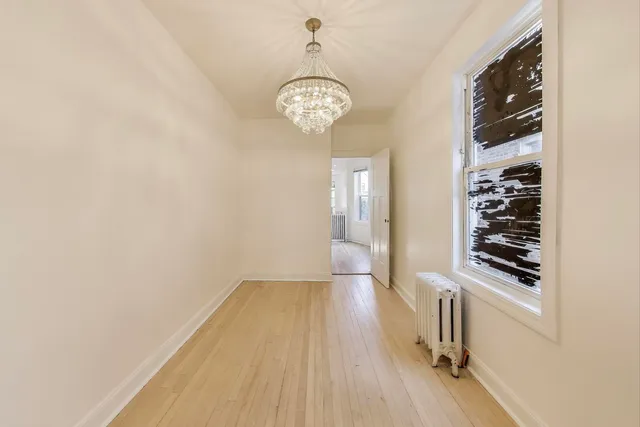 an empty room with wooden floor mirror and windows