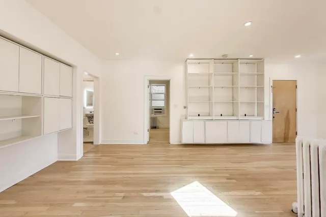 a view of an empty room with cabinet and entryway