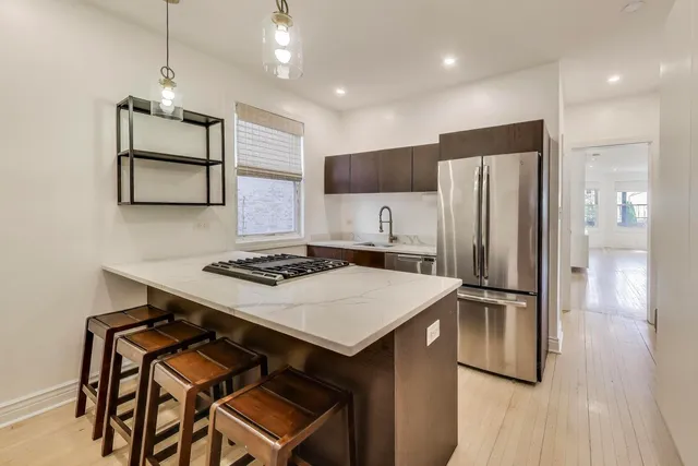 a kitchen that has a kitchen island wooden cabinets and stainless steel appliances