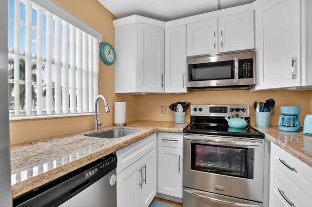 a kitchen with granite countertop white cabinets stainless steel appliances and a sink