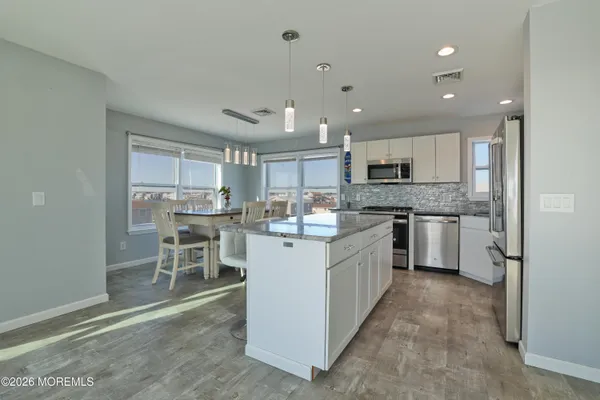 a kitchen with stainless steel appliances kitchen island granite countertop a stove top oven a sink a dining table and chairs