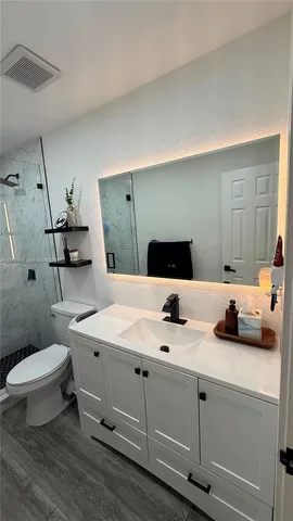 a bathroom with a granite countertop toilet sink and mirror