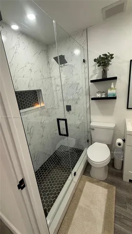a bathroom with a granite countertop sink a toilet and a shower