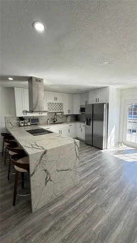 a kitchen with stainless steel appliances kitchen island granite countertop a stove a sink and a refrigerator