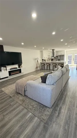 a living room with furniture a flat screen tv and kitchen view