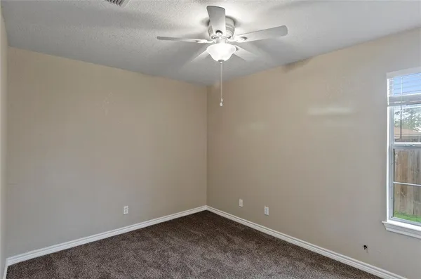 an empty room with windows and fan