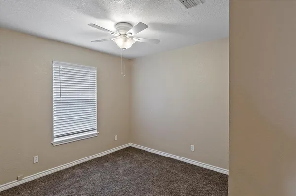 an empty room with windows and chandelier fan