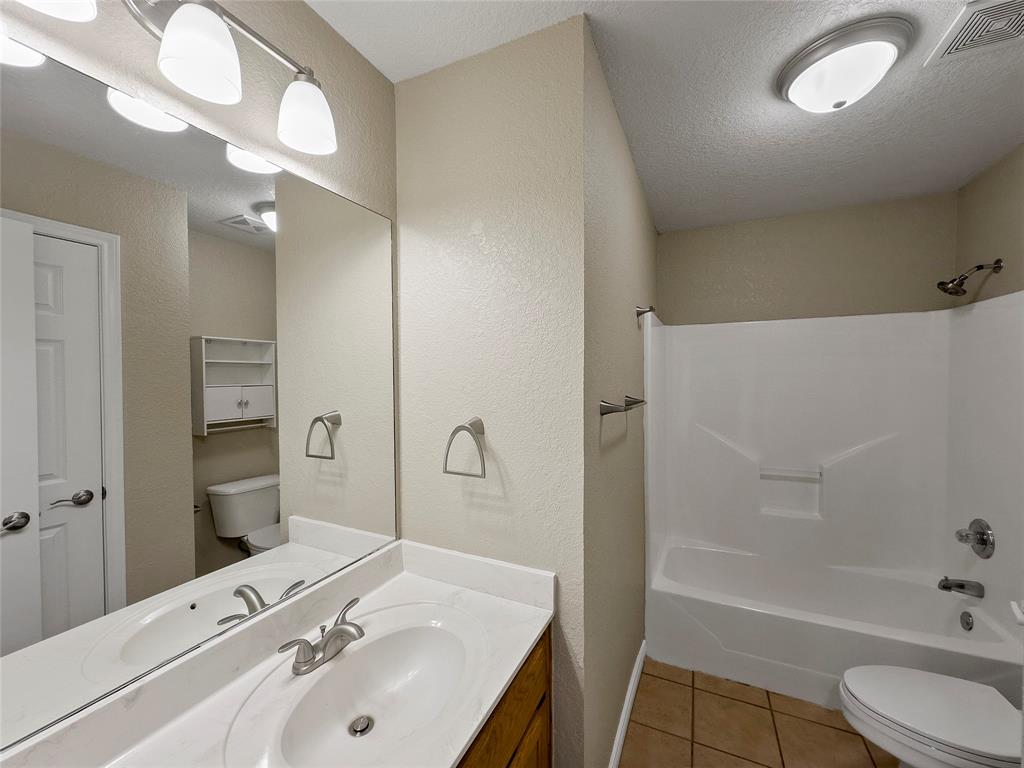 225 Oak Court, Unit 225 Rhome, TX 76078 - Photo 19 of 30 a bathroom with a tub sink toilet and mirror