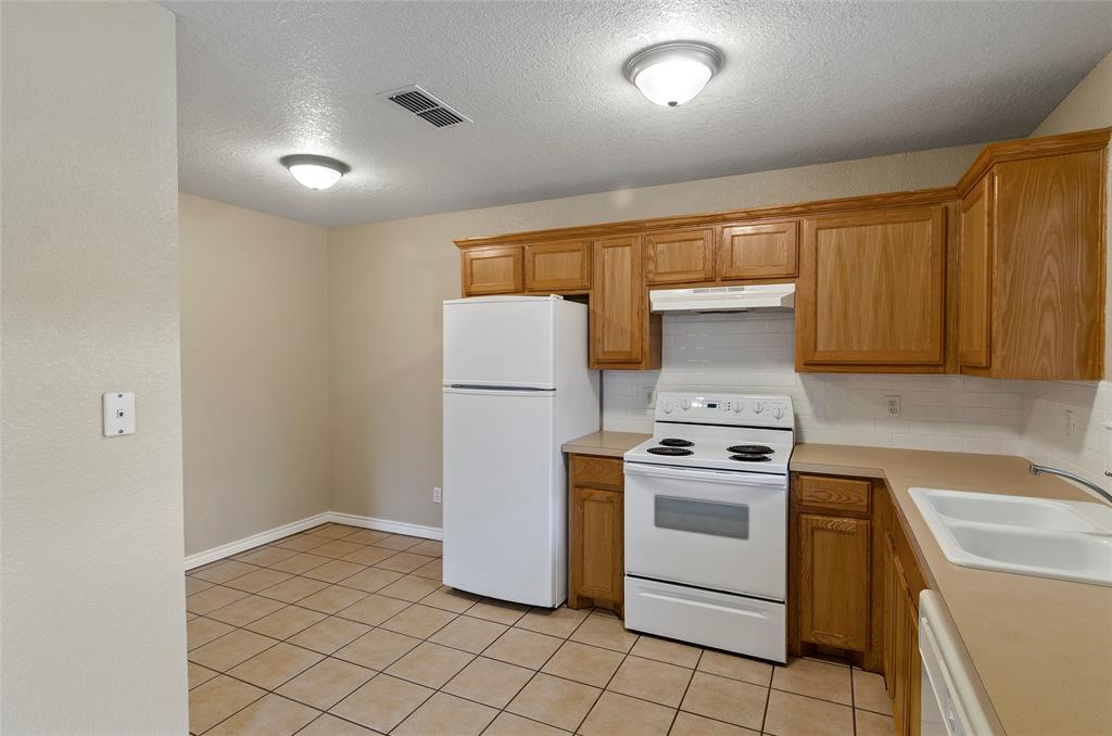 225 Oak Court, Unit 225 Rhome, TX 76078 - Photo 7 of 30 a kitchen with a stove a sink and a refrigerator