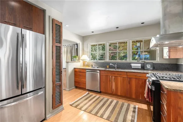 a kitchen with stainless steel appliances granite countertop a refrigerator a sink and wooden cabinets