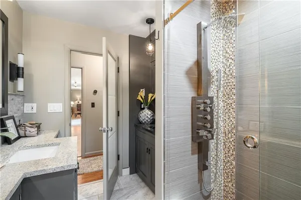a bathroom with a granite countertop shower a sink and a mirror