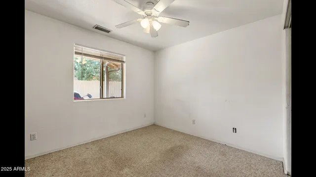 an empty room with a window and a fan