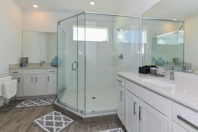 a bathroom with a double vanity sink mirror and shower