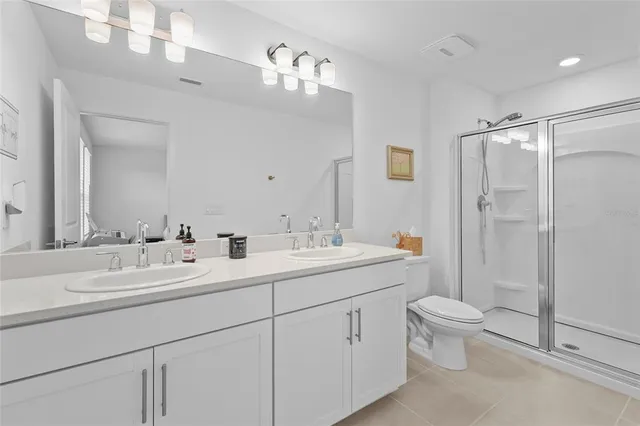 a bathroom with a double vanity sink toilet mirror and shower
