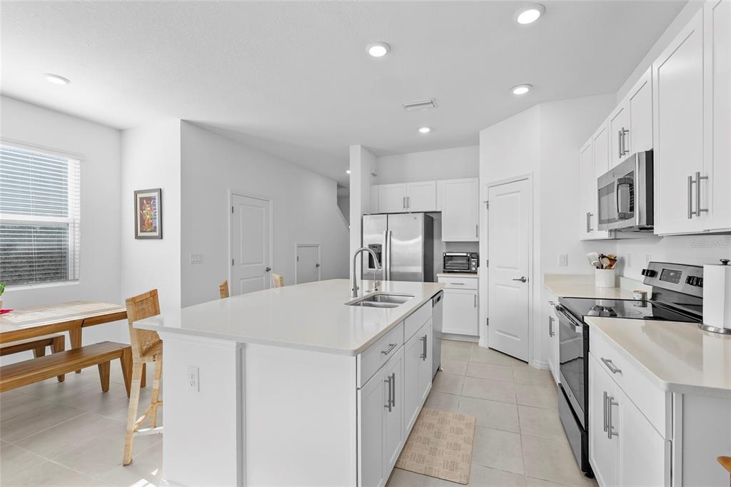 8564 Lunar Skye Street Sarasota, FL 34241 - Photo 6 of 44 a large white kitchen with stainless steel appliances lots of white furniture