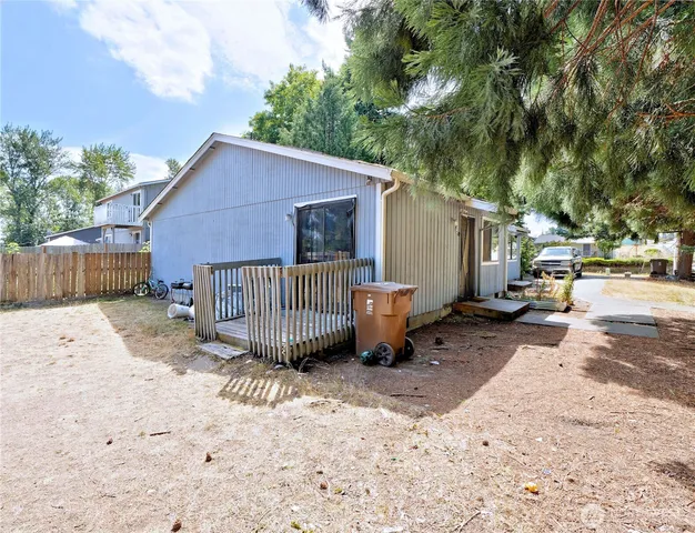a view of a small house with wooden fence next to a road