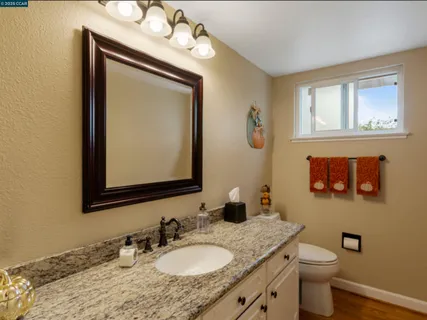 a bathroom with a granite countertop toilet a sink and mirror