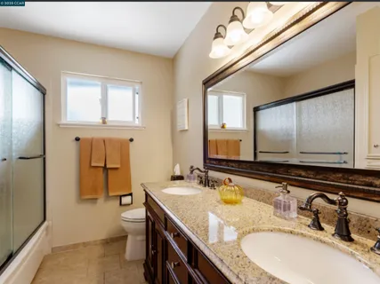 a bathroom with a granite countertop sink a toilet a mirror and shower