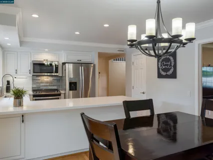 a kitchen with stainless steel appliances kitchen island granite countertop a table chairs and a refrigerator