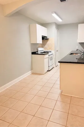 a kitchen with granite countertop a sink and a stove top oven