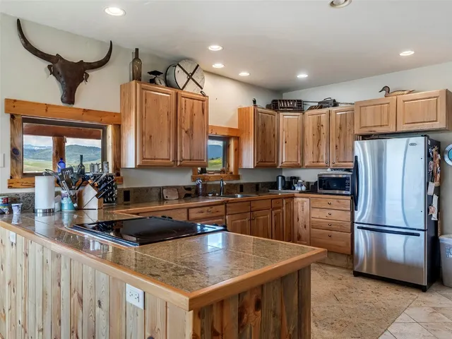 a kitchen with stainless steel appliances granite countertop a sink refrigerator and cabinets
