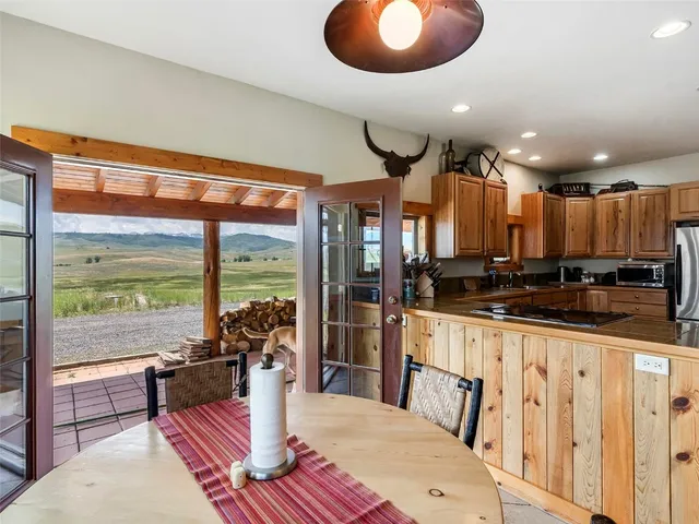 a kitchen with stainless steel appliances kitchen island granite countertop a stove a refrigerator a sink and a dining table with wooden floor