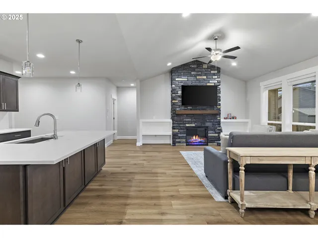 a large kitchen with stainless steel appliances granite countertop a stove refrigerator and a fireplace with wooden floor