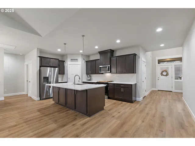 a large kitchen with kitchen island a sink wooden floor and stainless steel appliances