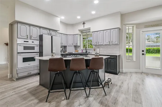 a kitchen with stainless steel appliances a dining table chairs and a refrigerator