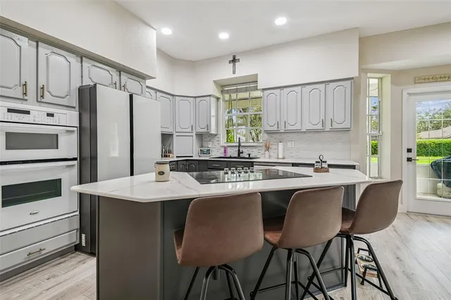 a kitchen with stainless steel appliances granite countertop a table chairs sink refrigerator and cabinets