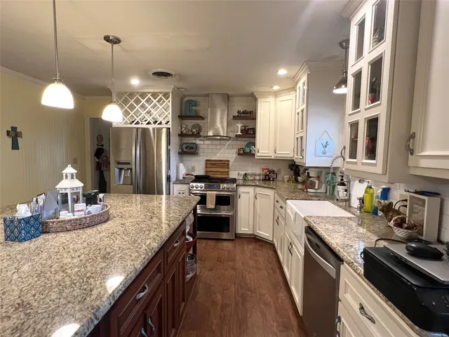 a kitchen with granite countertop kitchen island stainless steel appliances a sink stove and refrigerator