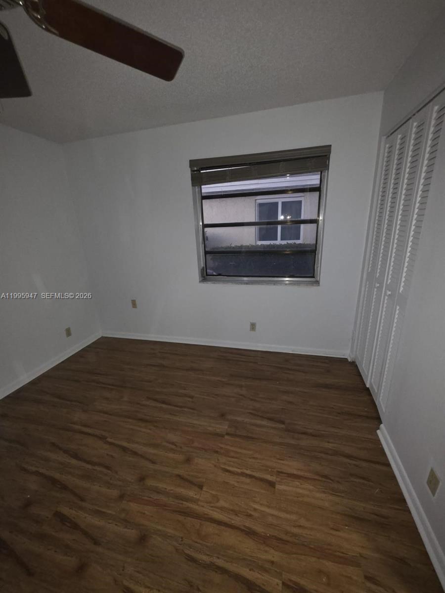 13731 Flora Place, Unit A Delray Beach, FL 33484 - Photo 20 of 21 a view of an empty room with wooden floor and a window
