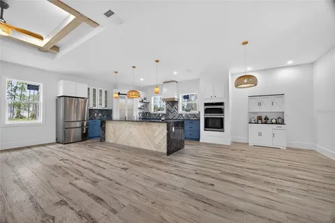 a view of an empty room with wooden floor and a ceiling fan