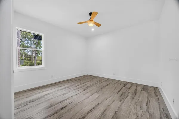 a view of empty room with wooden floor and ceiling fan