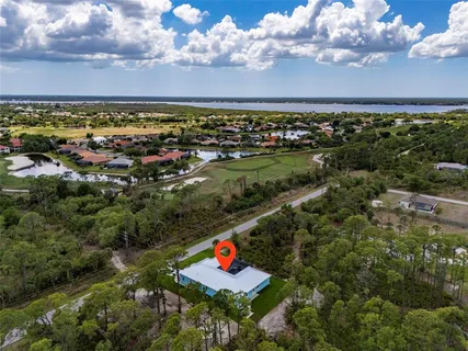 a white house with a big yard and large trees with wooden fence