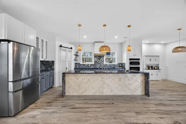a kitchen with a wooden floor and a view of living room
