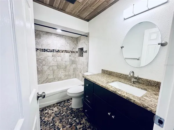 a bathroom with a granite countertop sink a toilet and shower