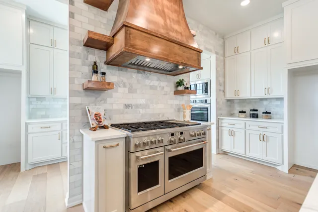 a large kitchen with white cabinets and chandelier