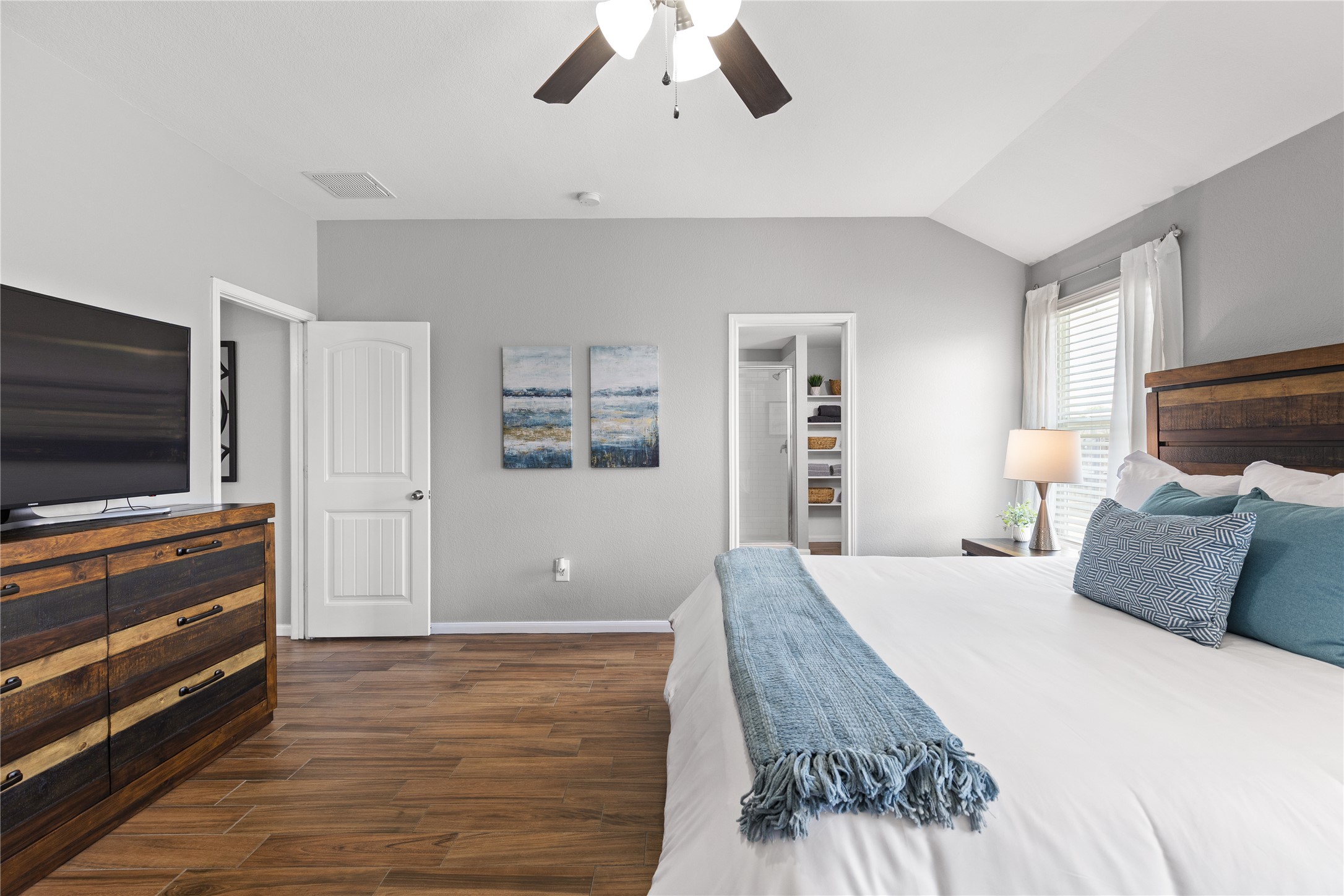 256 Alpha Kyle, TX 78640 - Photo 15 of 27 Hardwood look tile floors and a vaulted ceiling elevate this primary bedroom's comfortable design.