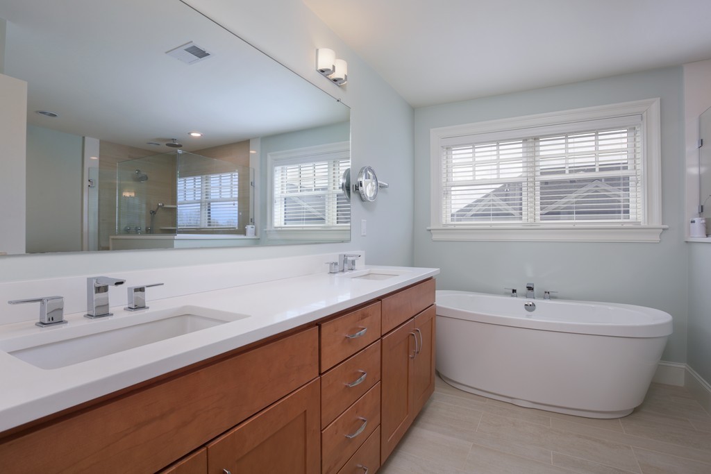 23 Lillian Way, Unit 28 Wayland, MA 01778 - Photo 7 of 16 a bathroom with a double vanity sink a mirror and a bathtub