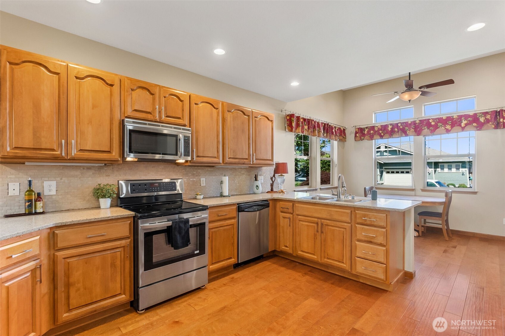 8650 Bainbridge Loop Northeast Lacey, WA 98516 - Photo 11 of 34 a kitchen with stainless steel appliances granite countertop wooden cabinets a sink a stove a dining table and chairs
