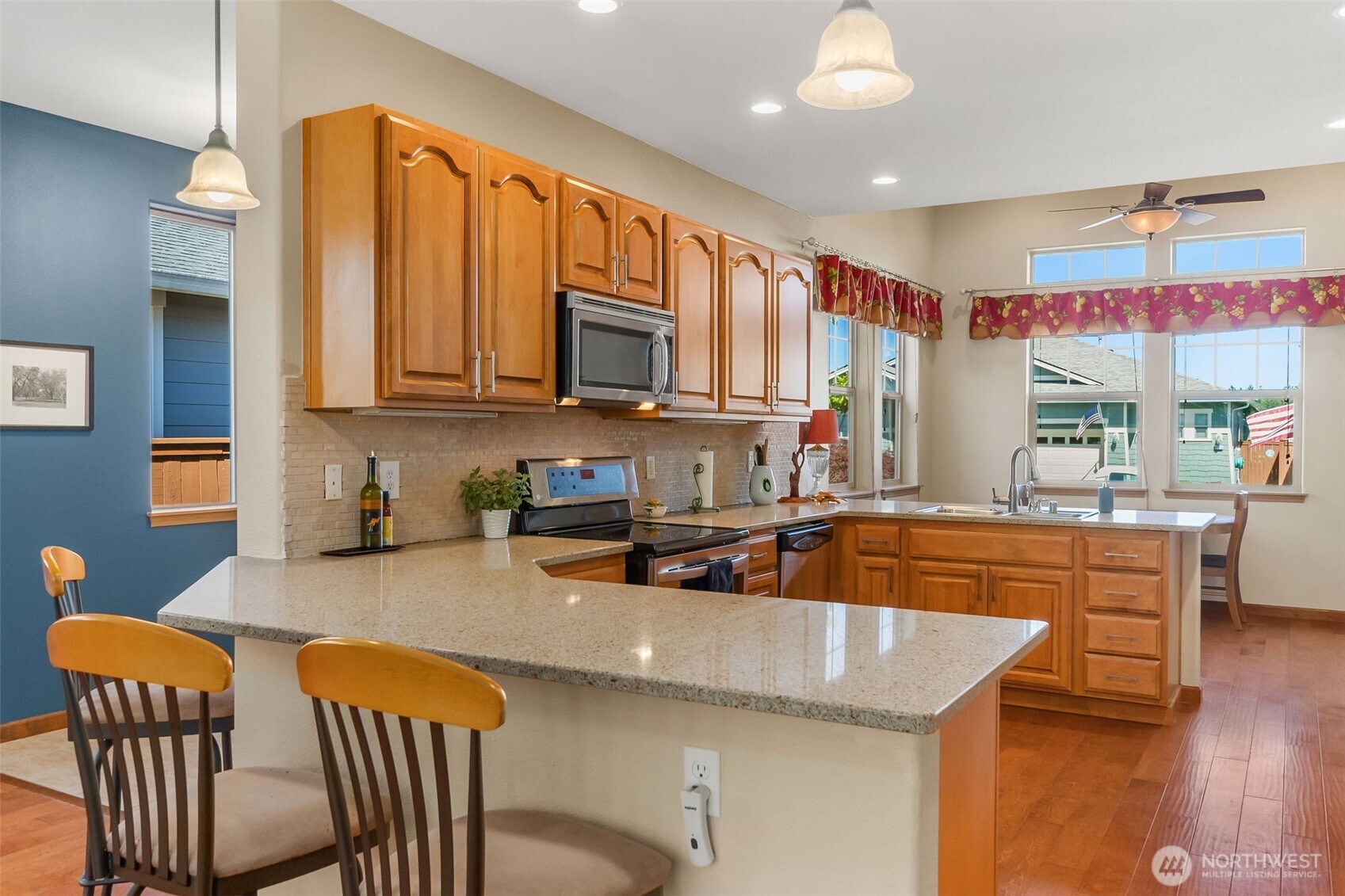 8650 Bainbridge Loop Northeast Lacey, WA 98516 - Photo 15 of 34 a kitchen with stainless steel appliances granite countertop a sink a stove a dining table and chairs with wooden floor