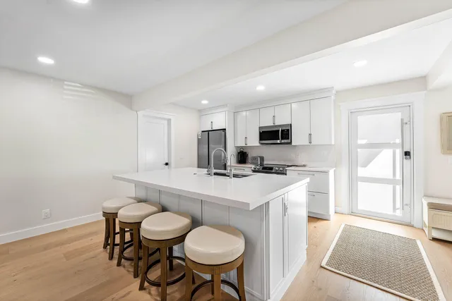 a kitchen with stainless steel appliances a white table chairs and a refrigerator
