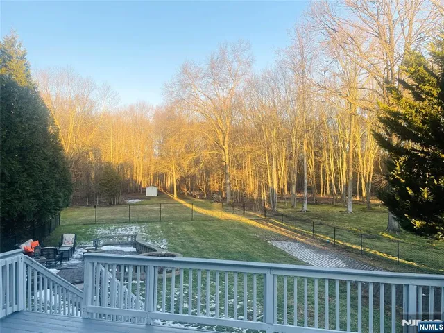 a view of a wooden deck with a big yard and large trees