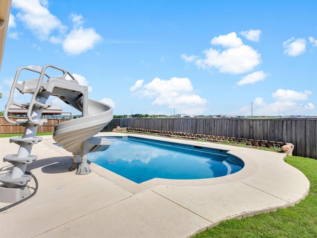 205 King George Road Ponder, TX 76259 - Photo 33 of 37 Curved inground pool with concrete decking, a spiral waterslide, and a wood privacy fence