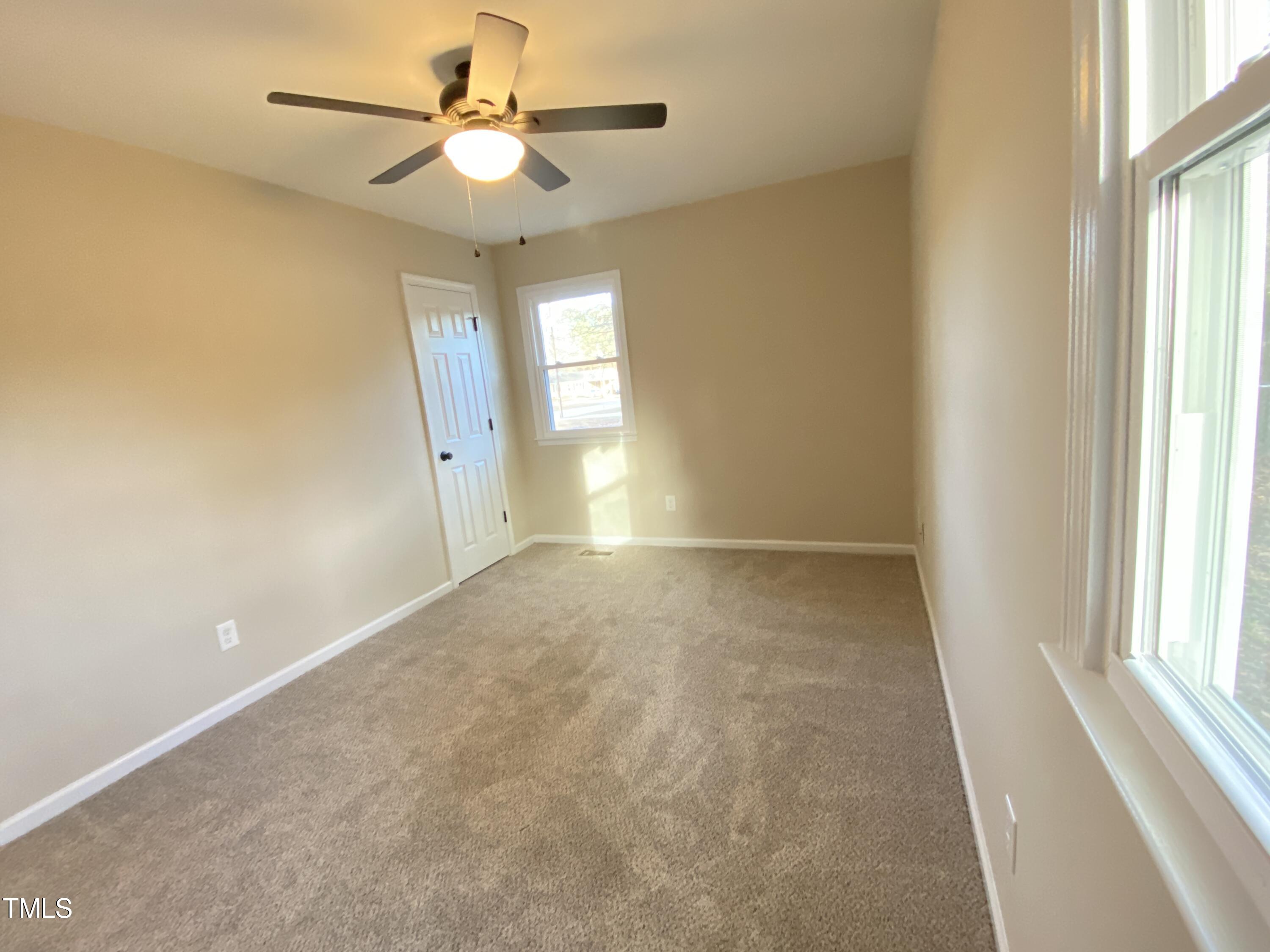 110 Sycamore Street Dunn, NC 28334 - Photo 20 of 28 en empty room with windows and chandelier fan