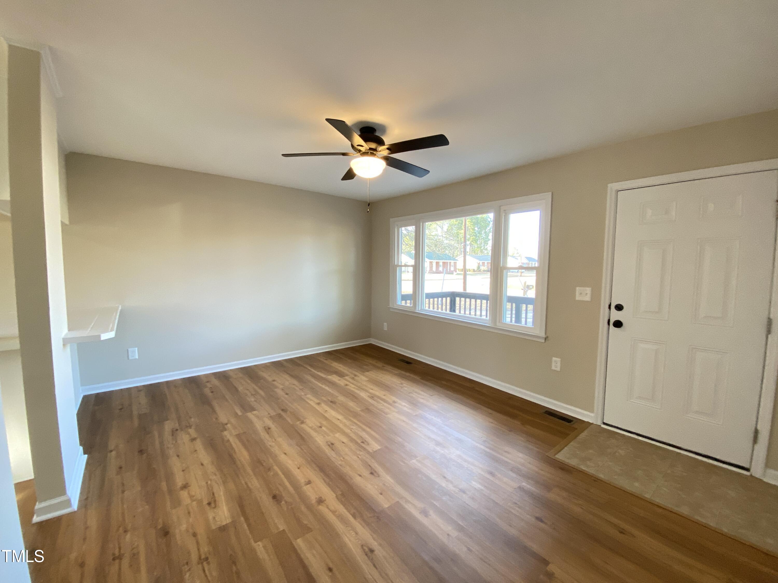 110 Sycamore Street Dunn, NC 28334 - Photo 4 of 28 an empty room with wooden floor and windows